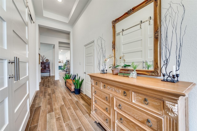 corridor with a barn door, baseboards, and wood finish floors