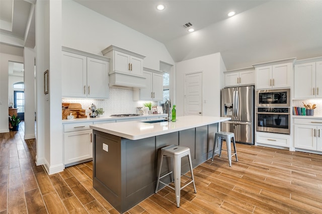 kitchen with wood finish floors, visible vents, appliances with stainless steel finishes, a breakfast bar area, and light countertops