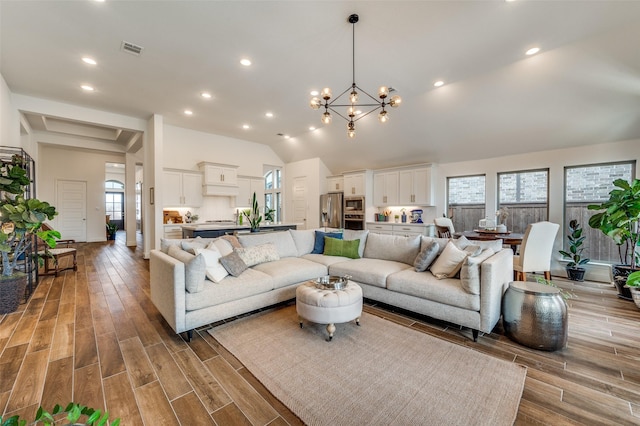 living area with wood finished floors, visible vents, lofted ceiling, recessed lighting, and a chandelier