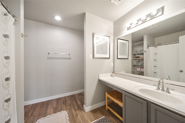 bathroom with vanity, wood finished floors, and baseboards