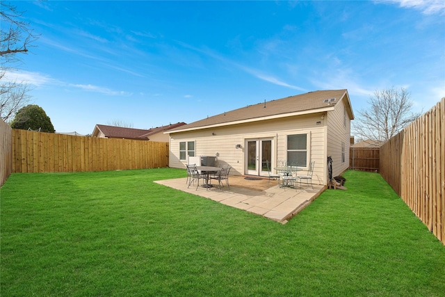 back of property featuring a patio, a lawn, a fenced backyard, and french doors