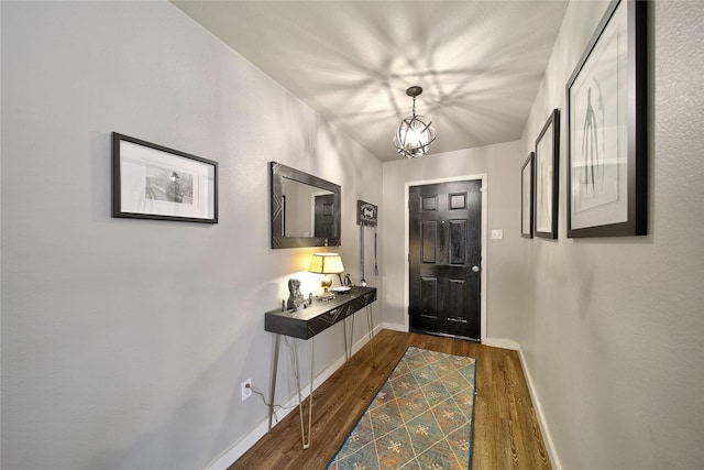 doorway to outside featuring baseboards, an inviting chandelier, and dark wood-style flooring