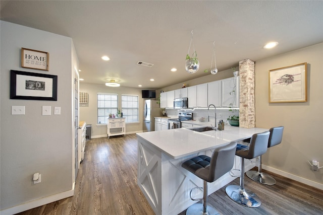 kitchen featuring a sink, appliances with stainless steel finishes, white cabinets, light countertops, and decorative backsplash