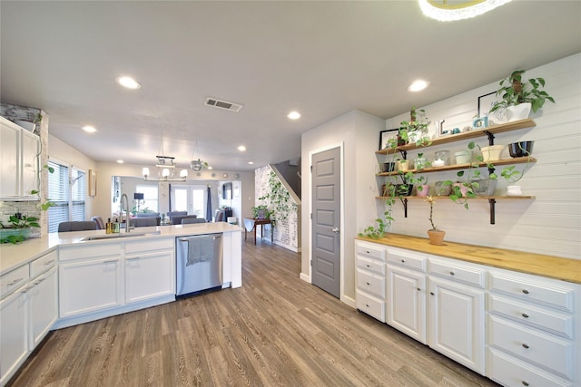 kitchen featuring visible vents, light wood-style flooring, stainless steel dishwasher, white cabinetry, and a sink