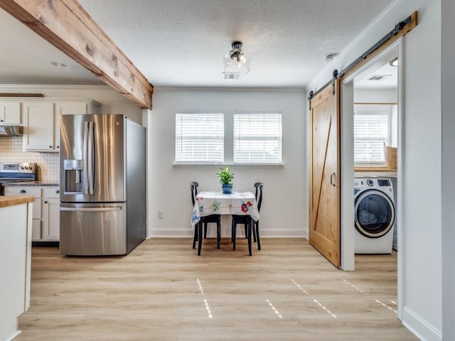 206 Cocopa Dr, Lake Kiowa, TX 76240 - kitchen featuring appliances with stainless steel finishes, washer / clothes dryer, a barn door, wall chimney range hood, and plenty of natural light
