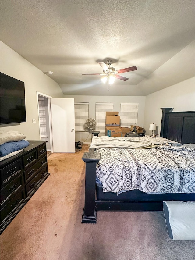 bedroom with light colored carpet, ceiling fan, vaulted ceiling, and a textured ceiling