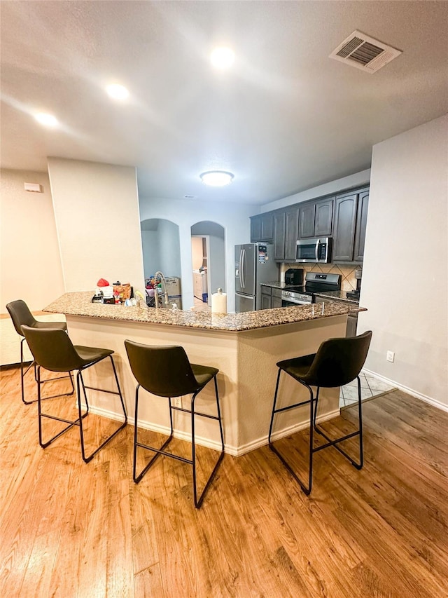 kitchen featuring light wood finished floors, visible vents, a breakfast bar area, and stainless steel appliances