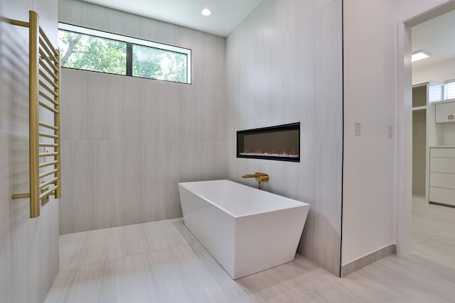 1733 E Lake Dr, Weatherford, TX 76087 - full bathroom featuring a soaking tub, a glass covered fireplace, recessed lighting, and tile walls
