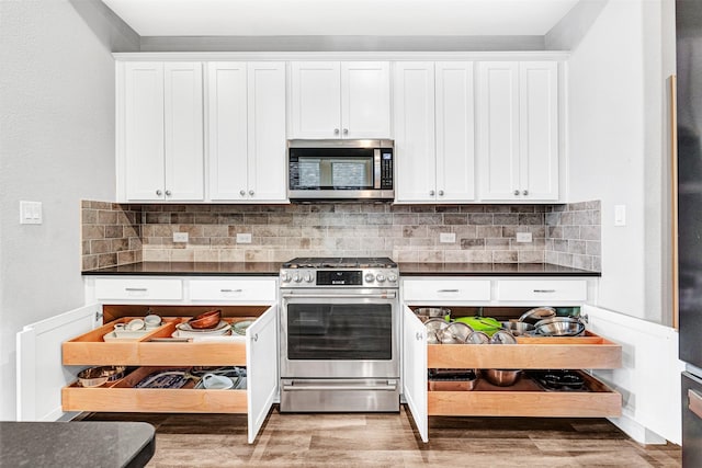 kitchen featuring dark countertops, tasteful backsplash, white cabinetry, and appliances with stainless steel finishes