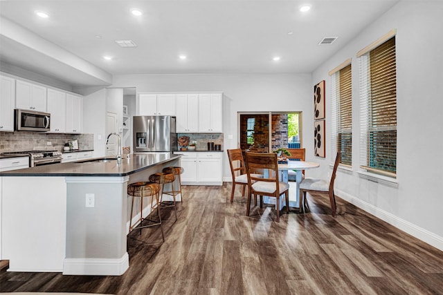 kitchen with visible vents, baseboards, a sink, dark countertops, and stainless steel appliances