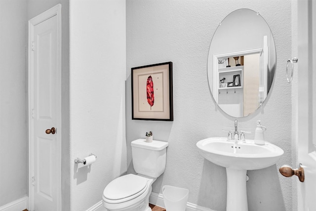 half bath with baseboards and toilet