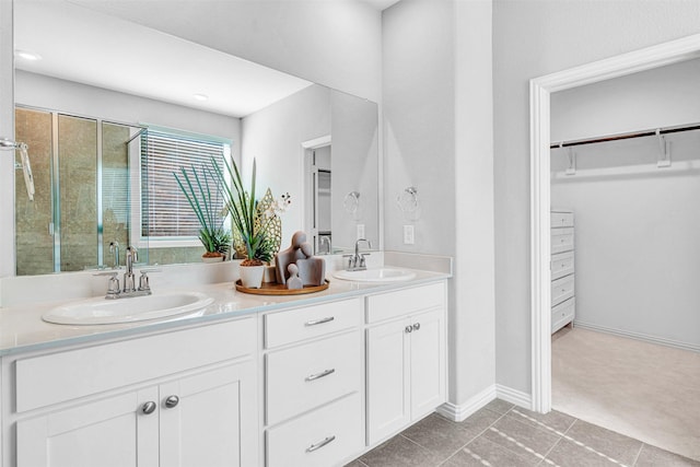 full bathroom with a shower with door, a walk in closet, double vanity, and a sink