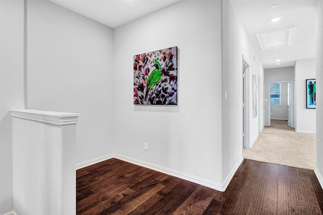 hallway with baseboards, attic access, and dark wood finished floors