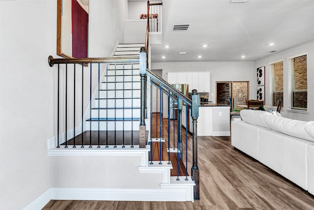 staircase with visible vents, baseboards, recessed lighting, and wood finished floors
