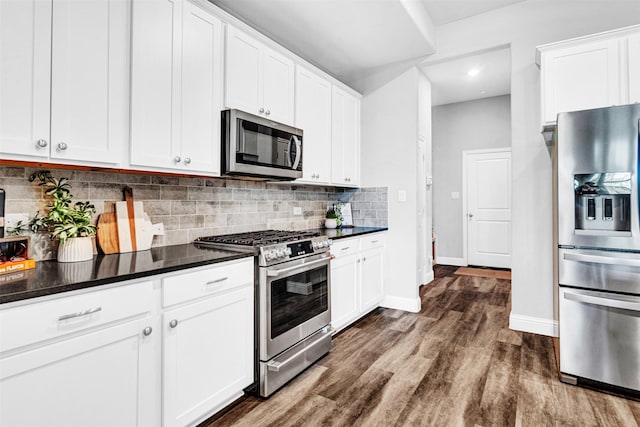 kitchen featuring white cabinets, appliances with stainless steel finishes, dark wood-style flooring, dark countertops, and backsplash