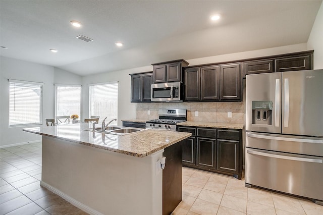 kitchen with lofted ceiling, light tile patterned flooring, a sink, decorative backsplash, and appliances with stainless steel finishes