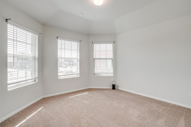 spare room with light carpet, lofted ceiling, and baseboards