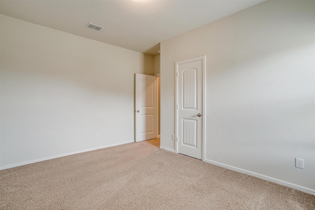 empty room featuring visible vents, light colored carpet, and baseboards