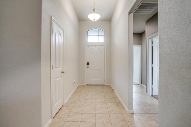 entrance foyer with light tile patterned floors, visible vents, baseboards, and a textured wall