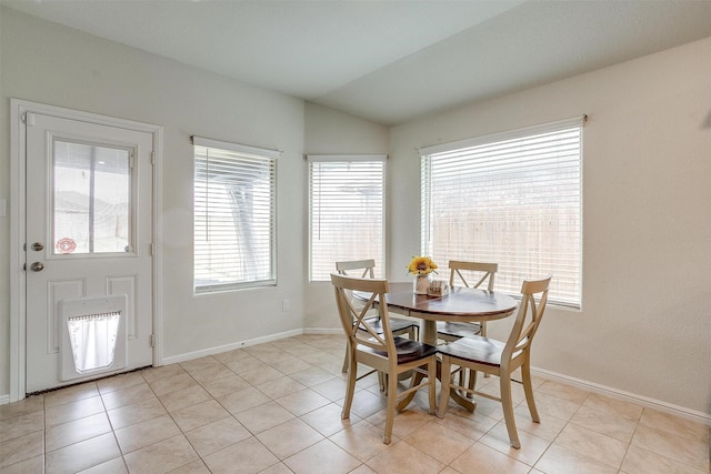 dining space with light tile patterned floors, baseboards, and lofted ceiling