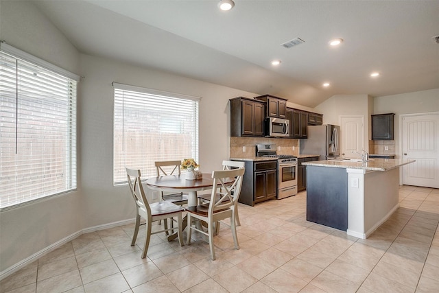 kitchen with visible vents, light tile patterned flooring, stainless steel appliances, dark brown cabinetry, and backsplash