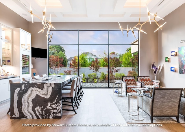 dining space featuring coffered ceiling, an inviting chandelier, and wood finished floors