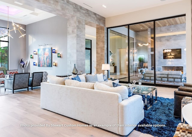 living area featuring a notable chandelier, a tile fireplace, a towering ceiling, and wood finished floors