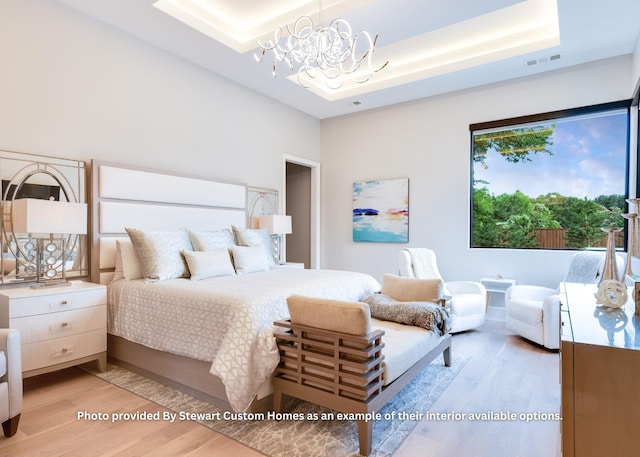 bedroom featuring a tray ceiling, visible vents, a chandelier, and light wood finished floors