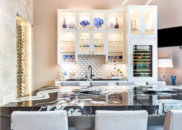 bar featuring indoor wet bar, wine cooler, tasteful backsplash, and a sink