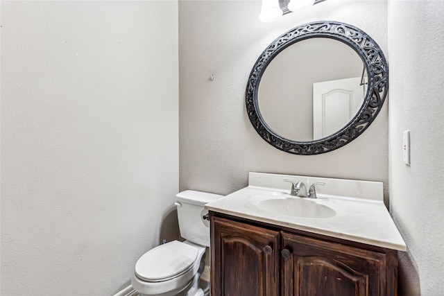 bathroom featuring toilet, vanity, and a textured wall