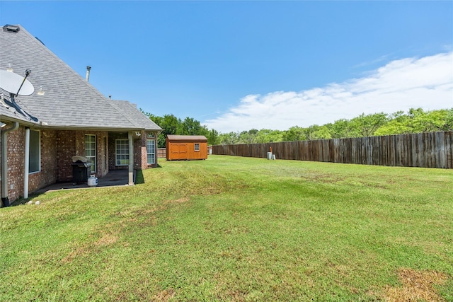 view of yard with an outdoor structure, a storage shed, and a fenced backyard
