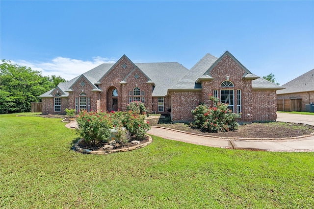 view of front of property featuring brick siding, a front lawn, and a shingled roof