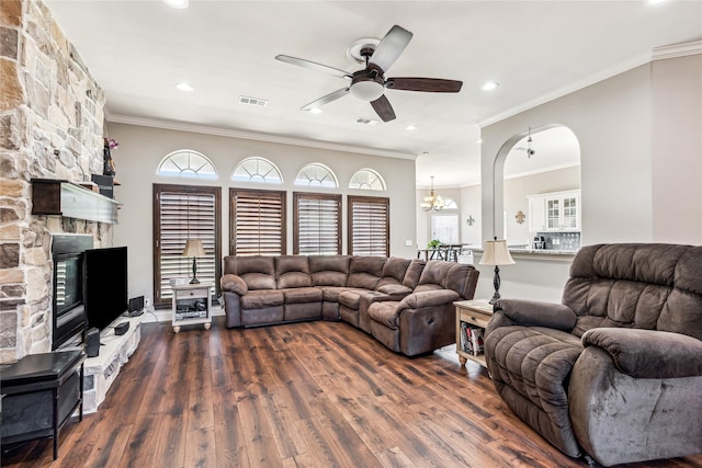 living room with visible vents, a fireplace, arched walkways, dark wood-type flooring, and ceiling fan with notable chandelier
