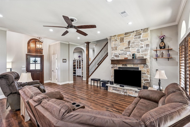 living room with visible vents, crown molding, ceiling fan, a fireplace, and wood finished floors