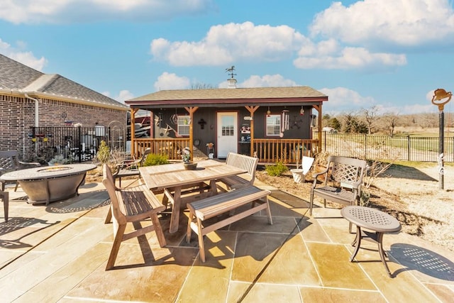 view of patio featuring outdoor dining space, fence, and a fire pit