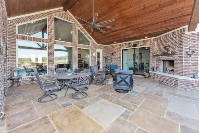 view of patio with ceiling fan, outdoor dining space, and an outdoor brick fireplace