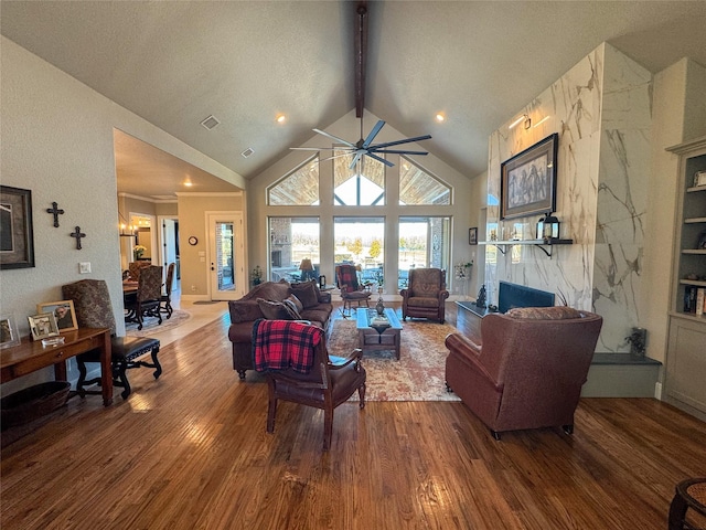 living room featuring beam ceiling, visible vents, a ceiling fan, and wood finished floors