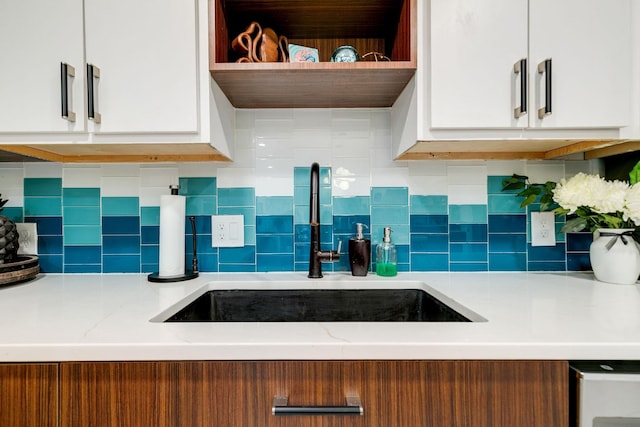 kitchen featuring a sink, decorative backsplash, modern cabinets, and white cabinets