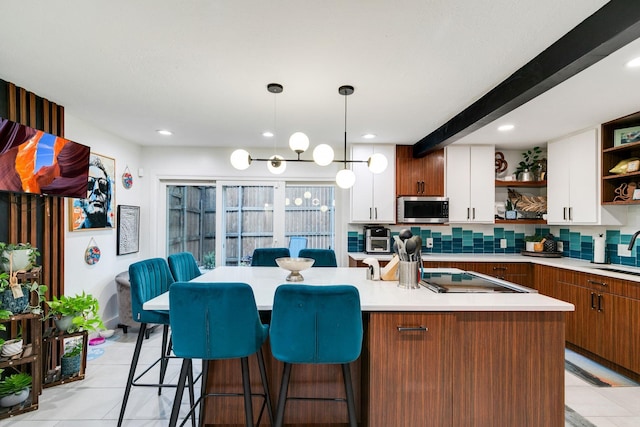 kitchen featuring open shelves, stainless steel microwave, a sink, backsplash, and white cabinetry