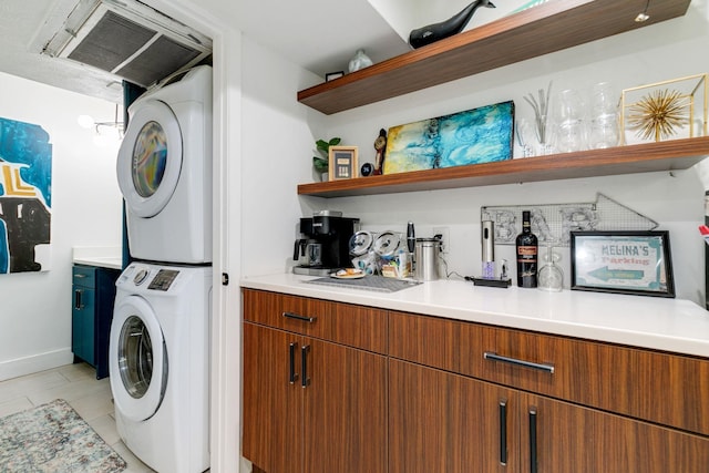 laundry room with baseboards, visible vents, laundry area, light tile patterned flooring, and stacked washer and dryer
