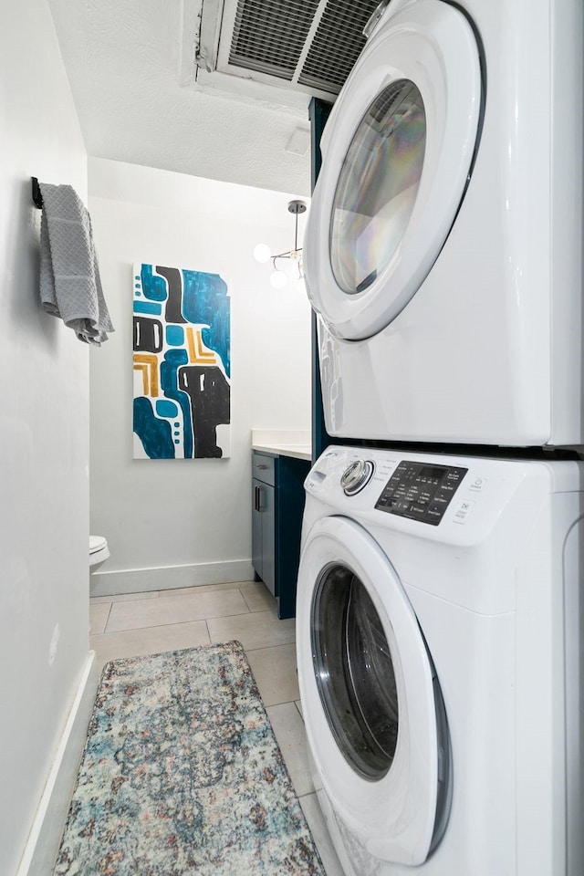 clothes washing area featuring laundry area, baseboards, and stacked washing maching and dryer