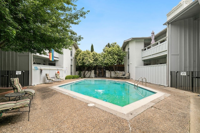 pool with a patio area and fence