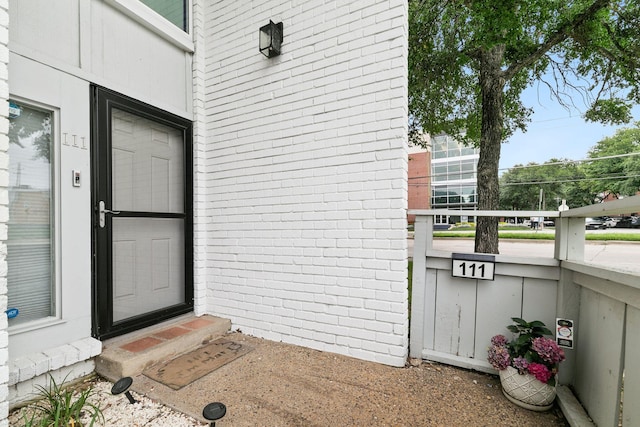 entrance to property with brick siding and a balcony