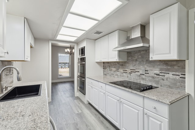 4018 Tobin Trl, Rowlett, TX 75088 - kitchen with wall chimney exhaust hood, a sink, black electric stovetop, a chandelier, and light wood-style floors