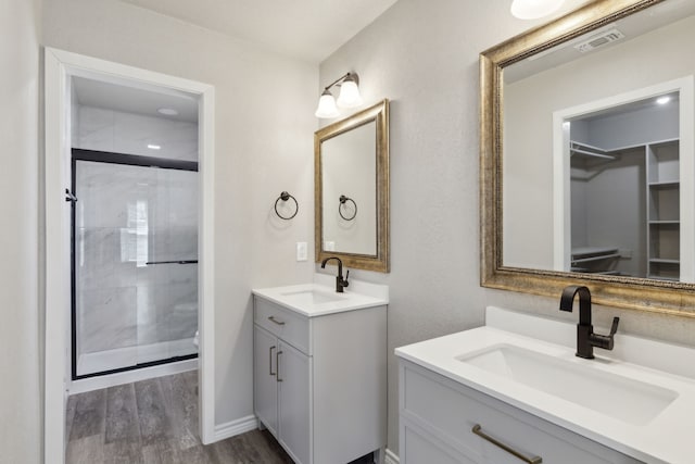 4018 Tobin Trl, Rowlett, TX 75088 - full bathroom featuring wood finished floors, two vanities, a shower stall, and a walk in closet