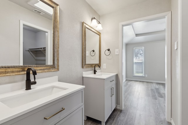 4018 Tobin Trl, Rowlett, TX 75088 - full bathroom featuring two vanities, wood finished floors, and baseboards