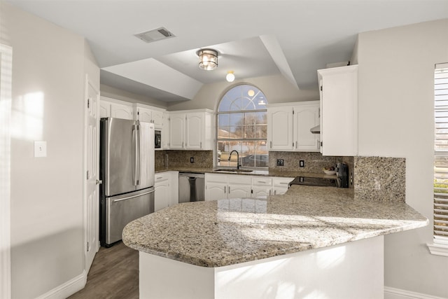 kitchen with visible vents, a sink, baseboards, a peninsula, and appliances with stainless steel finishes