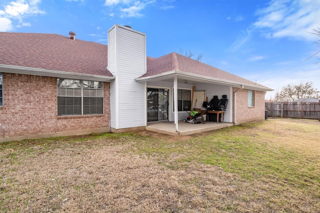 back of property with a chimney, fence, a yard, a patio, and brick siding