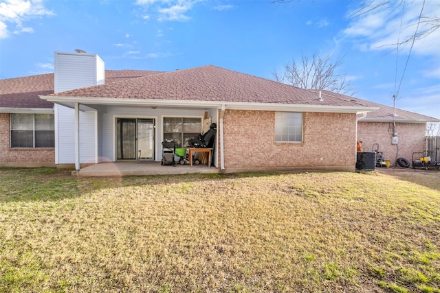 rear view of house featuring central AC, a patio area, a chimney, a yard, and brick siding