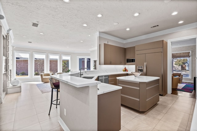 5819 Coolwater Cv, Dallas, TX 75252 - kitchen featuring a center island, crown molding, a sink, light tile patterned floors, and built in microwave